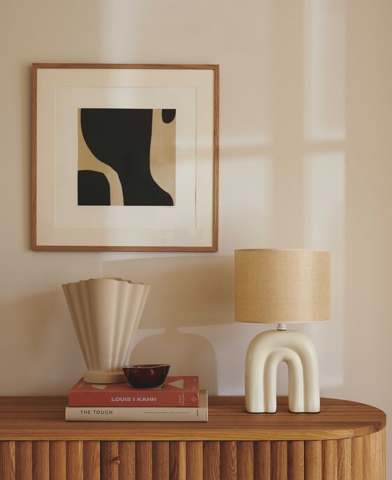 Stolní lampička Haze kombinuje keramiku a lněné stínítko, které dodává interiéru měkké světlo. Dostupné v béžové barvě.