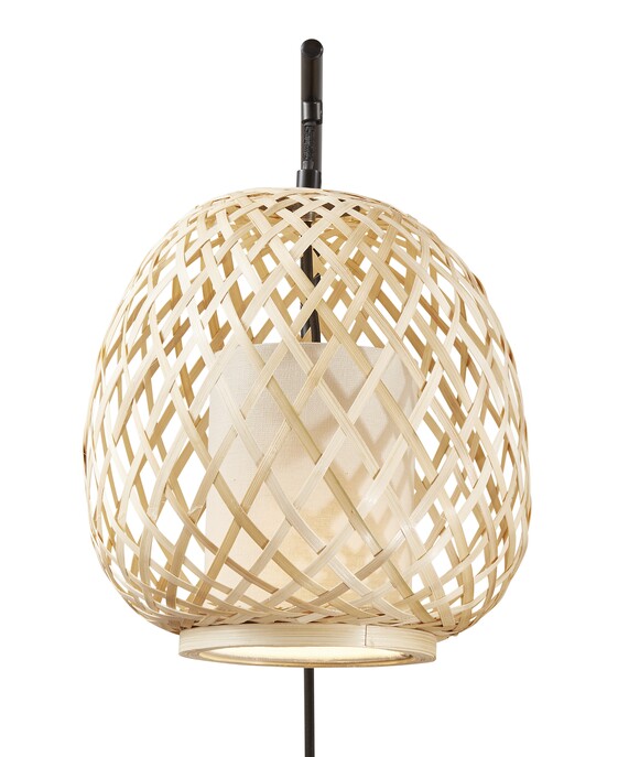 Nástěnné svítidlo Hisoka kombinuje bambusová vlákna a látkové stínítko. Svítidlo vydává měkké světlo, vhodné do obývacího pokoje.
